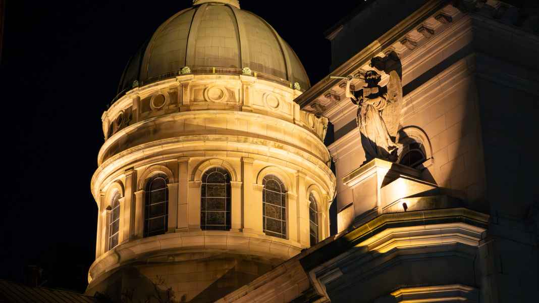Night view of lit church dome and statue at Saint John Baptiste in NYC